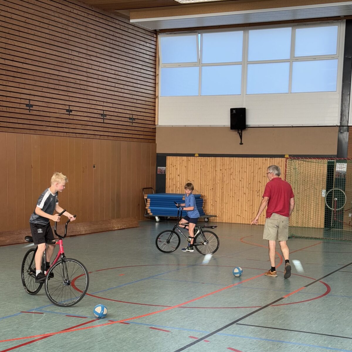 2 Radball spielende Kinder plus Übungsleiter